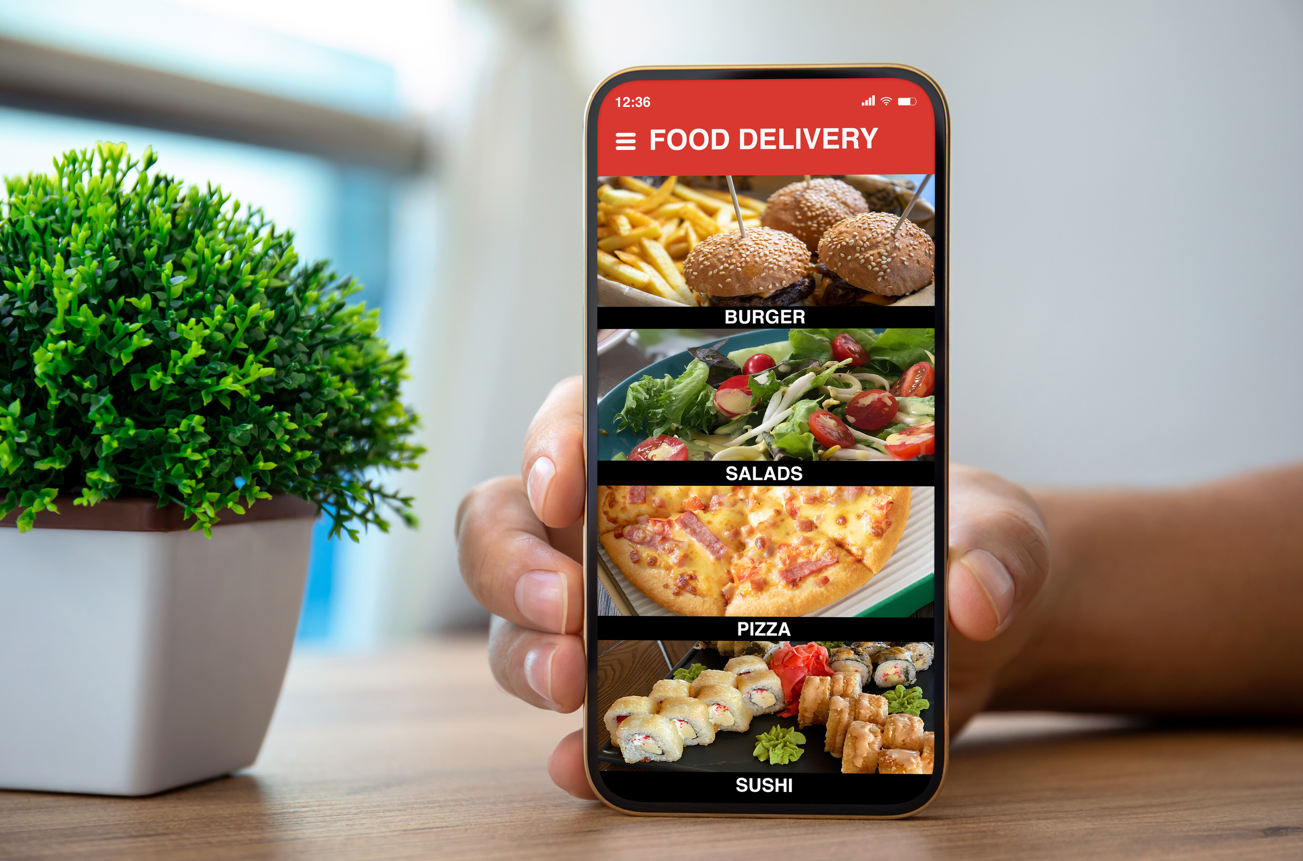 male hands holding phone with food delivery app over table